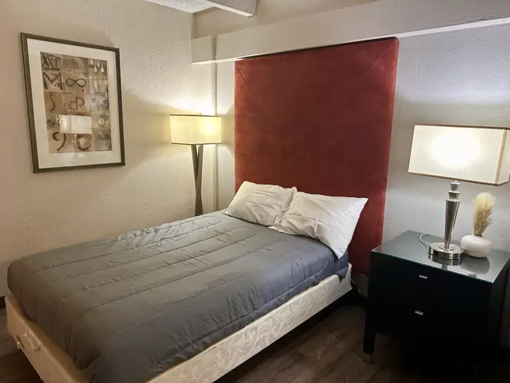 Bed with gray bedding and a red headboard between two lamps