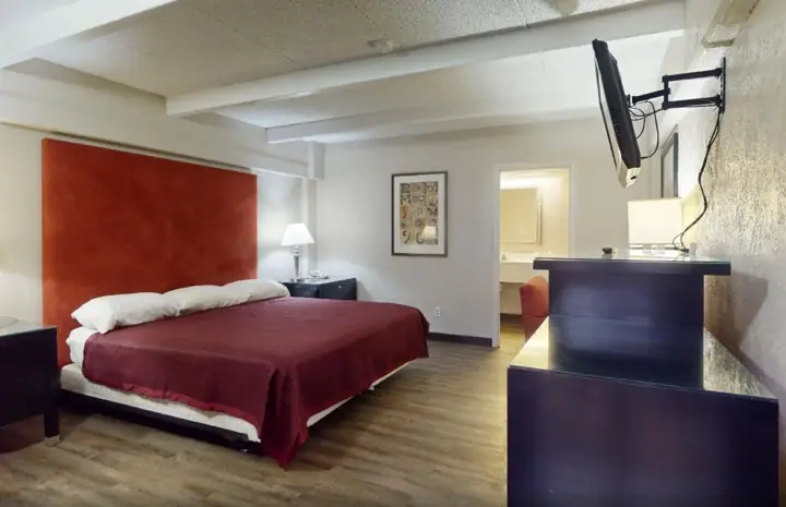 King room with a red headboard and a wall-mounted TV
