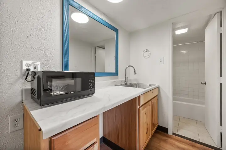 Kitchenette counter with a microwave and sink beside the bathroom