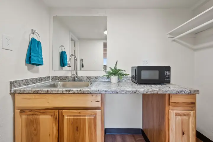 Kitchenette counter with a sink, wood cabinets and a microwave