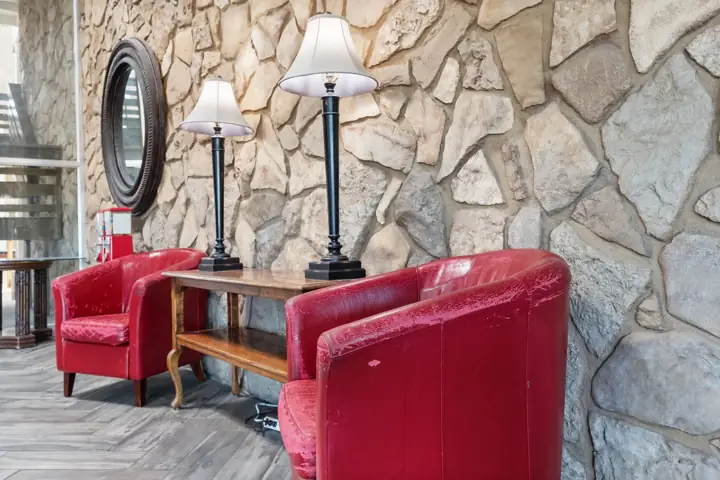 Lobby seating with red leather chairs and a stone wall
