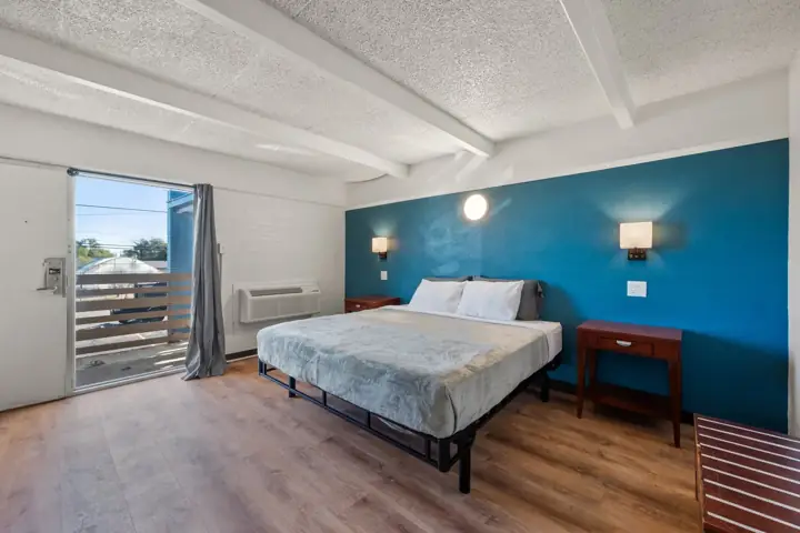 Renovated king room with a blue accent wall, wood floors and a door to the balcony