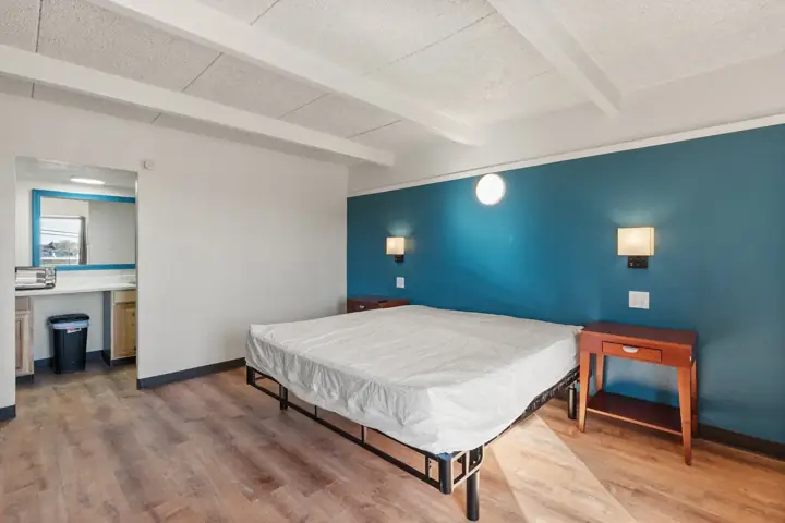 Renovated room with a blue accent wall, bed and kitchenette area