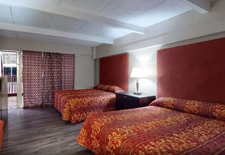Room with two beds and patterned red bedspreads