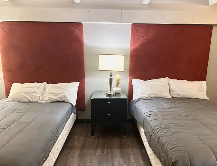 Two queen beds with gray bedding and red headboards